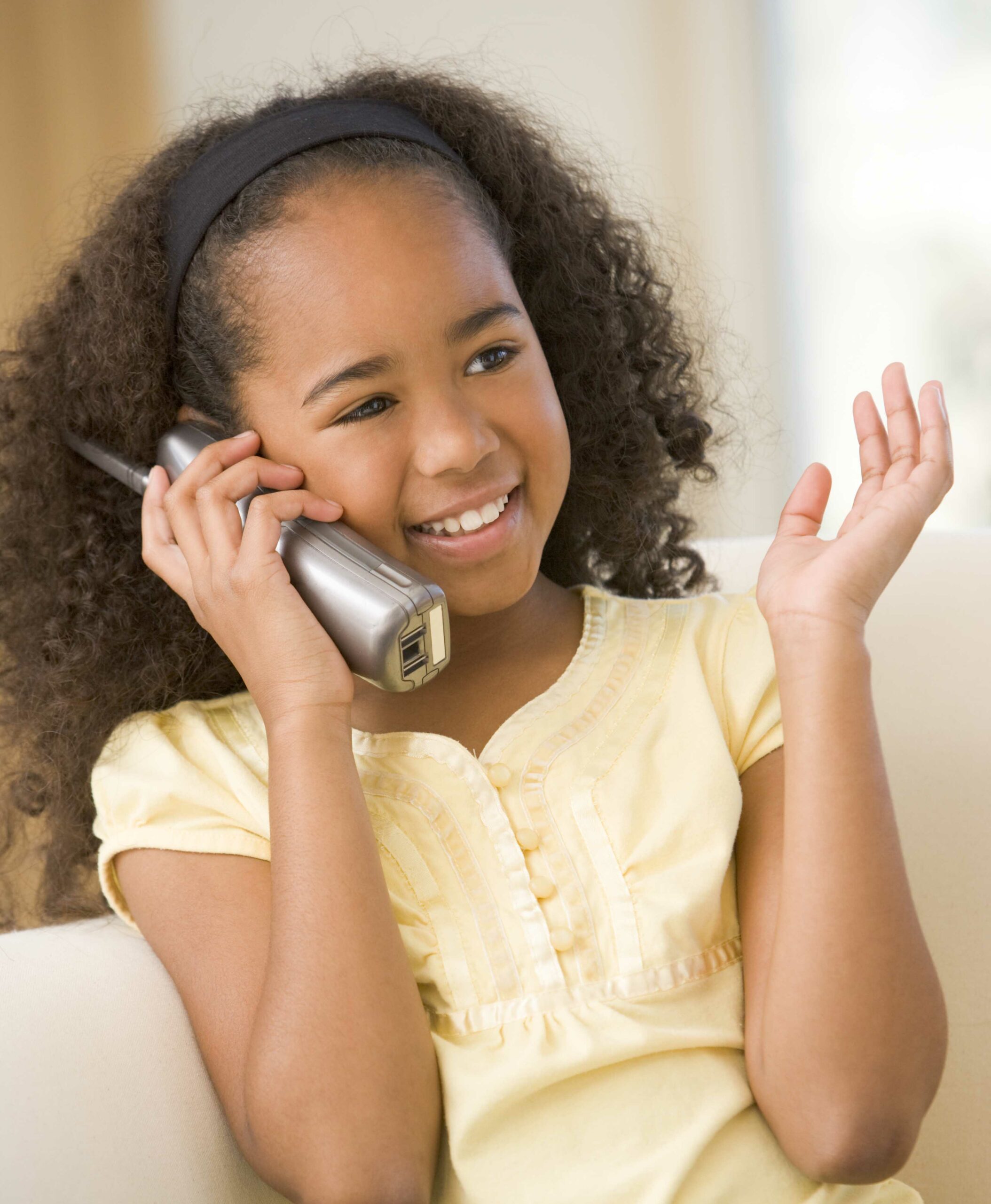 Young girl in living room using telephone and smiling
